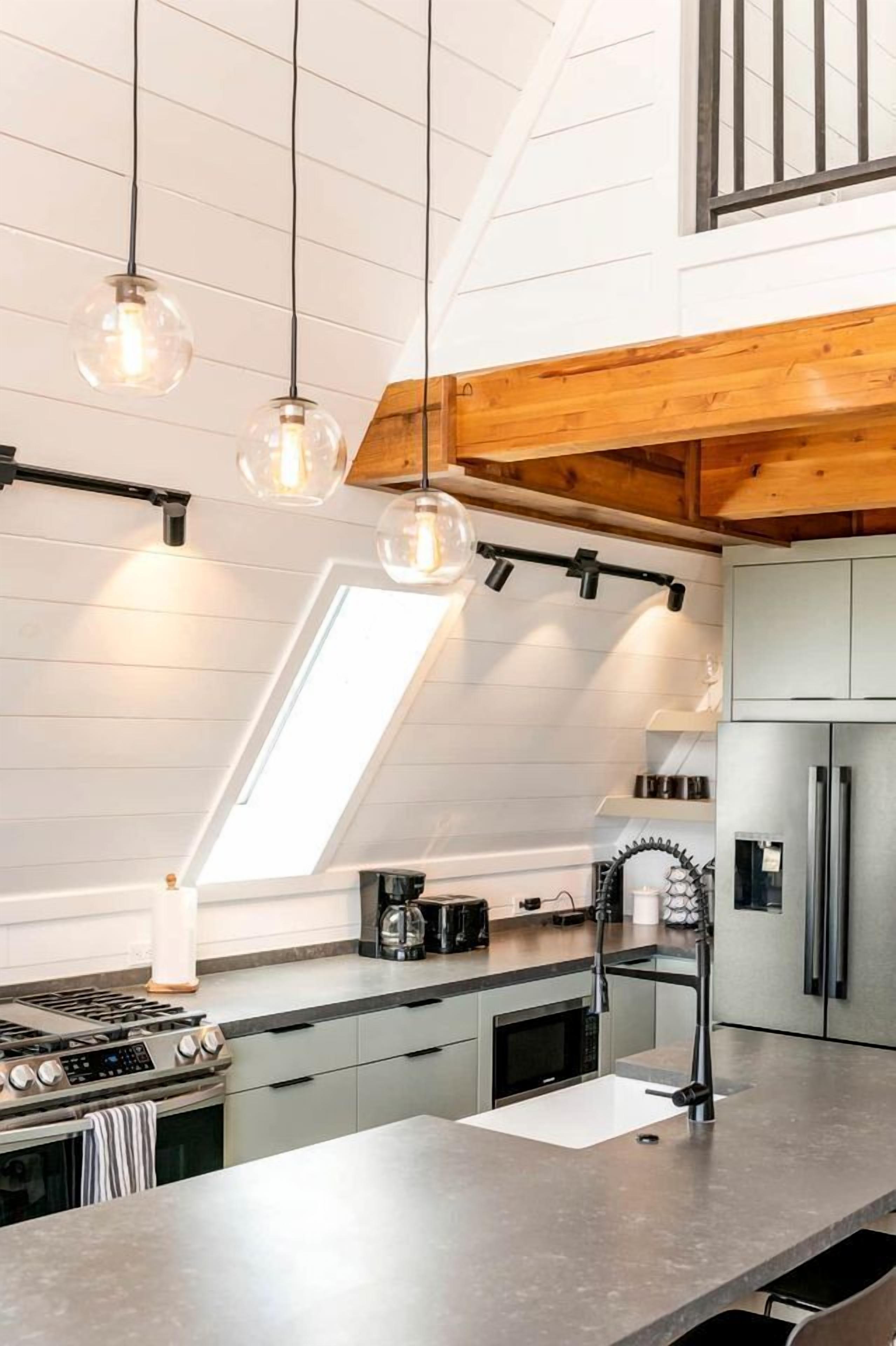 A modern kitchen with a skylight, stainless steel appliances, and pendant lighting.