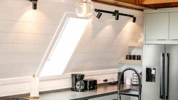 A modern kitchen with a skylight, stainless steel appliances, and pendant lighting.