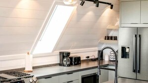 A modern kitchen with a skylight, stainless steel appliances, and pendant lighting.