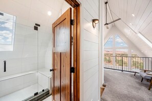 A modern bathroom with a glass shower enclosure, a wooden door, and a balcony with a view of the desert. - Secluded A-frame with Stunning Desert Views in Torrey, Utah (Torrey)