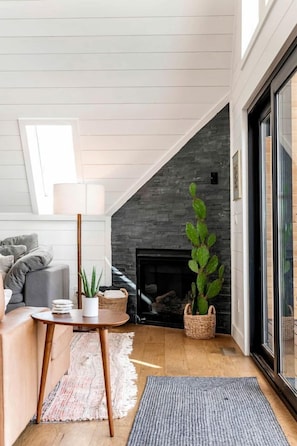 A cozy living room with a fireplace, a sofa, a lamp, and a large plant. - Secluded A-frame with Stunning Desert Views in Torrey, Utah (Torrey)