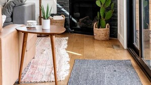 A cozy living room with a fireplace, a sofa, a lamp, and a large plant.