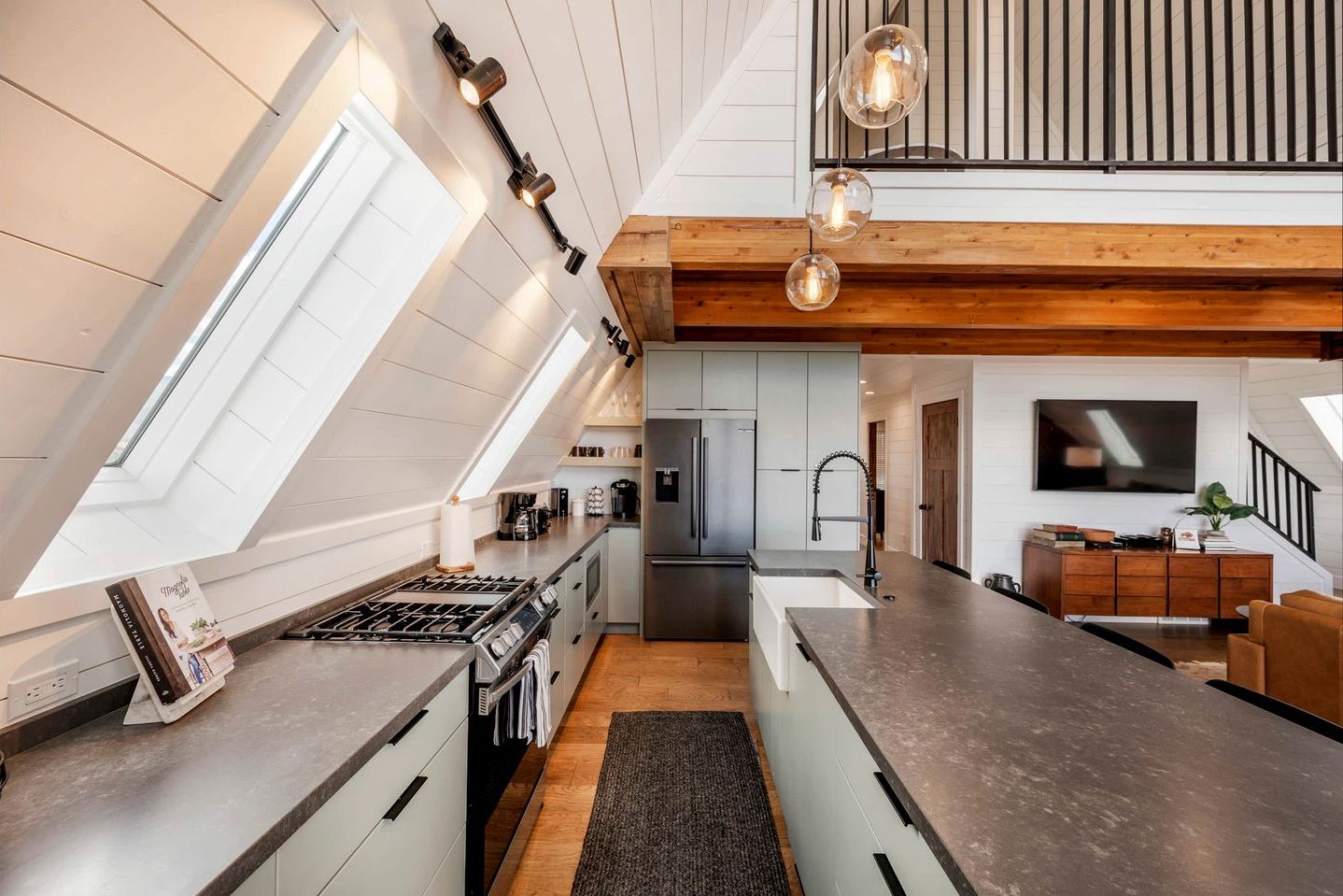 A modern kitchen with a skylight, a central island, and a dining area with a TV.