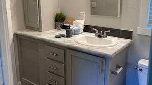 A bathroom with a sink, mirror, cabinet, and toilet.