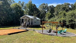 A house with a deck, a swing set, and a grill area.