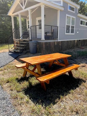 A house with a covered porch, a wooden picnic table, and a staircase leading to the entrance.