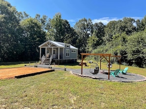 A house with a deck, a swing set, and a grill area.