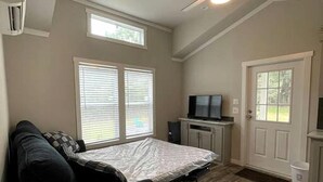 A compact room with a bed, a couch, a TV, and a ceiling fan.