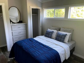 A bedroom with a bed, a dresser, a mirror, and a window.