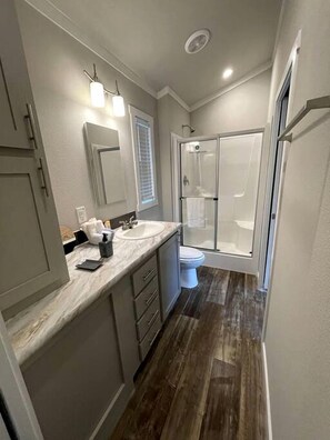 Un baño moderno con cabina de ducha, tocador con lavabo e inodoro.