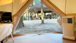 A tent with a table and an air conditioning unit inside, and a thatched structure outside. - Luxurious Safari Tent, Amazing for Glamping Vacations near Seguin, Texas (Seguin)