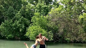A person standing on a paddleboard in a body of water surrounded by trees. - Luxurious Safari Tent, Amazing for Glamping Vacations near Seguin, Texas (Seguin)