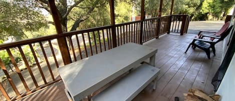 Un espace extérieur abrité, doté d’une terrasse en bois, d’un banc et d’une table.