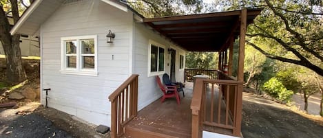 A small house with a porch, a chimney, and a red chair.