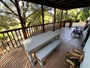 Ein überdachter Außenbereich mit Holzterrasse, einer Bank und einem Tisch.