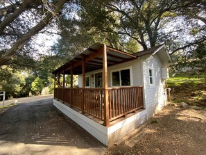 Eine kleine Holzhütte mit einer Holzterrasse, umgeben von Bäumen.