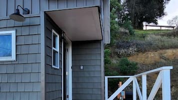 A house with a wooden deck, a white railing, and a gray exterior.