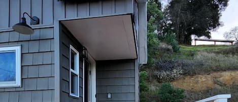 A house with a wooden deck, a white railing, and a gray exterior.