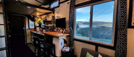 A compact kitchen with a large window, a television, and a view of a lake.