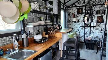 A compact kitchen with a wooden countertop, stainless steel appliances, and a black rug.