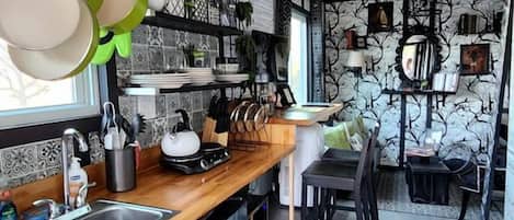 A compact kitchen with a wooden countertop, stainless steel appliances, and a black rug.