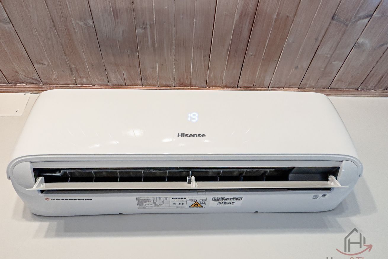 Un equipo de aire acondicionado Hisense blanco con panel de control y una etiqueta de advertencia.