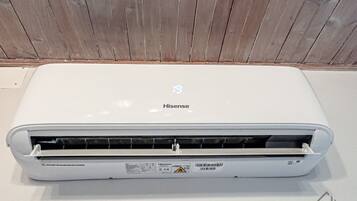 Un equipo de aire acondicionado Hisense blanco con panel de control y una etiqueta de advertencia.