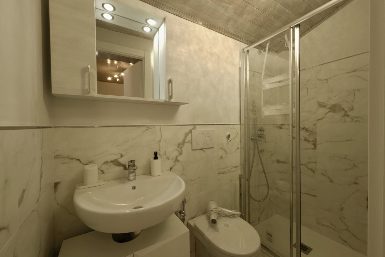 Une salle de bain avec un lavabo blanc, un miroir et une douche.