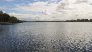 A calm lake with a wooden dock on the left and a forested shoreline.