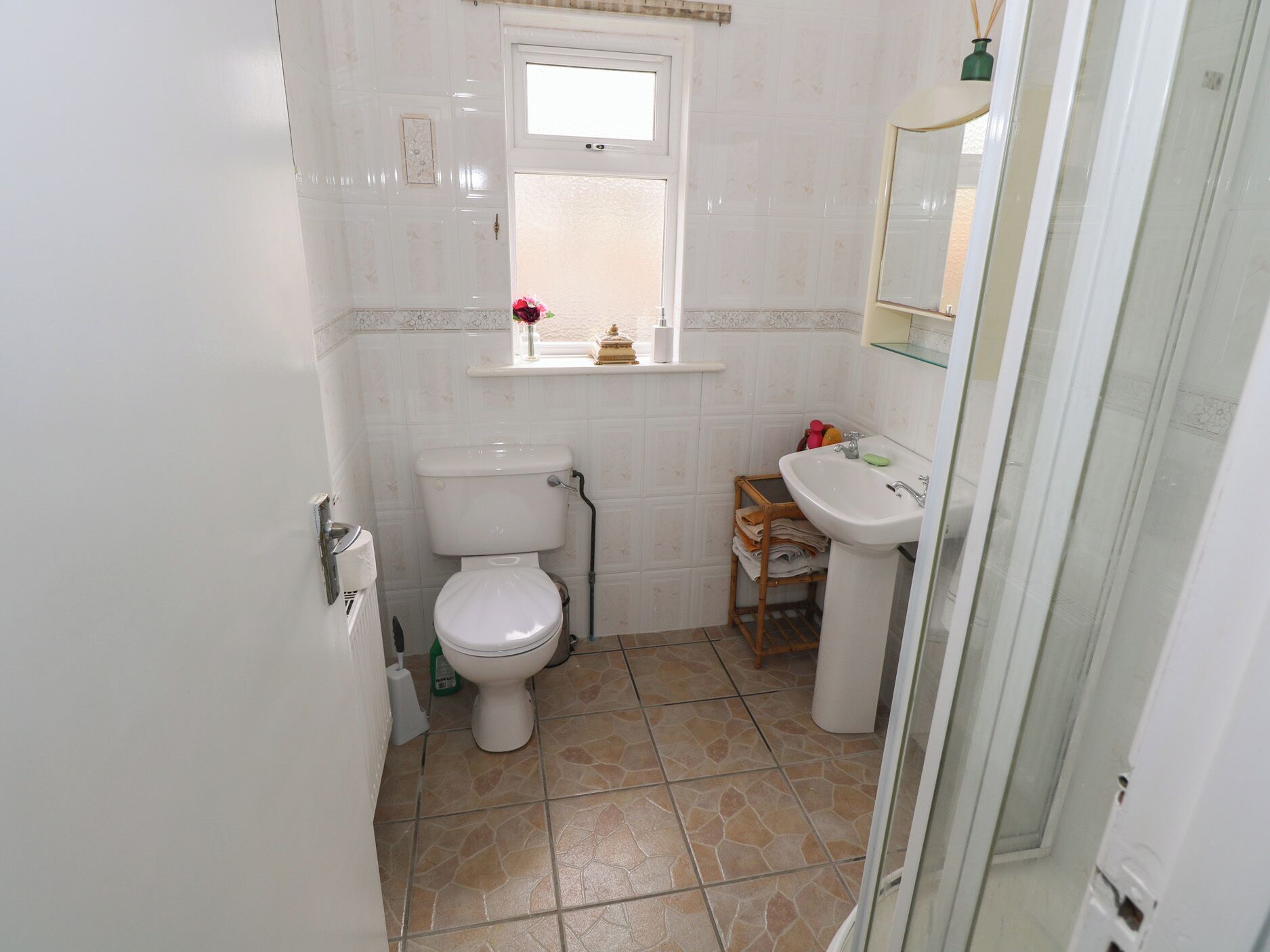 A bathroom with a toilet, sink, and window.