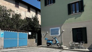 A scooter parked in front of a building with a blue shuttered entrance, a sign indicating private parking, and a wall-mounted sign. - Lake view & tranquillity, Villa Laguna Blue, whirlpool & sauna-10 minutes walk to the lake (Gardone Riviera)