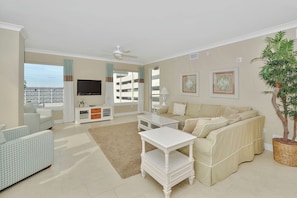A spacious living room with a beige sofa, a white coffee table, and a television on the wall. - Gateway Grand 401 Linens included in this stunning 4 BR 3 BA condo! (Ocean City)