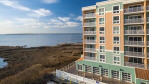 Un hotel de varios pisos con balcones, vistas a la playa y un estacionamiento.
