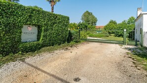 A gravel driveway leading to a gated entrance with a sign for 'Melloni Street Home Rooms.' - Melloni Street Home - Lavender Room (Dolo)