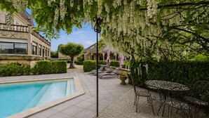 Un área de piscina con solárium empinado, sillas de descanso y una mesa con sillas.