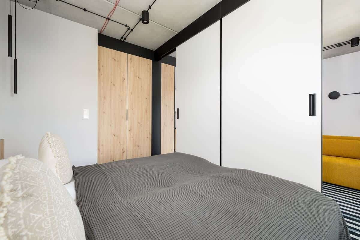 Un dormitorio con cama, armario de madera y sofá amarillo.