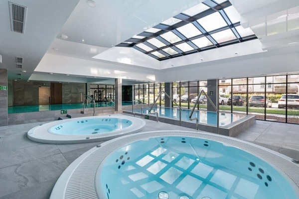 Indoor spa area featuring a circular jacuzzi under a glass ceiling.