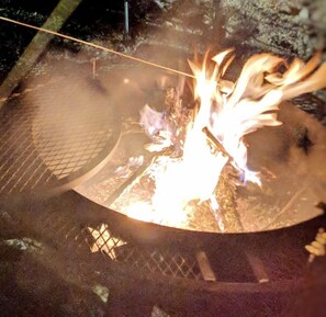 A campfire with flames, surrounded by a wire mesh.