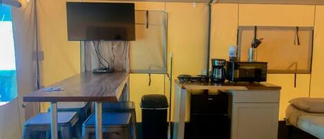A compact kitchen with a dining area, a small refrigerator, and a microwave.
