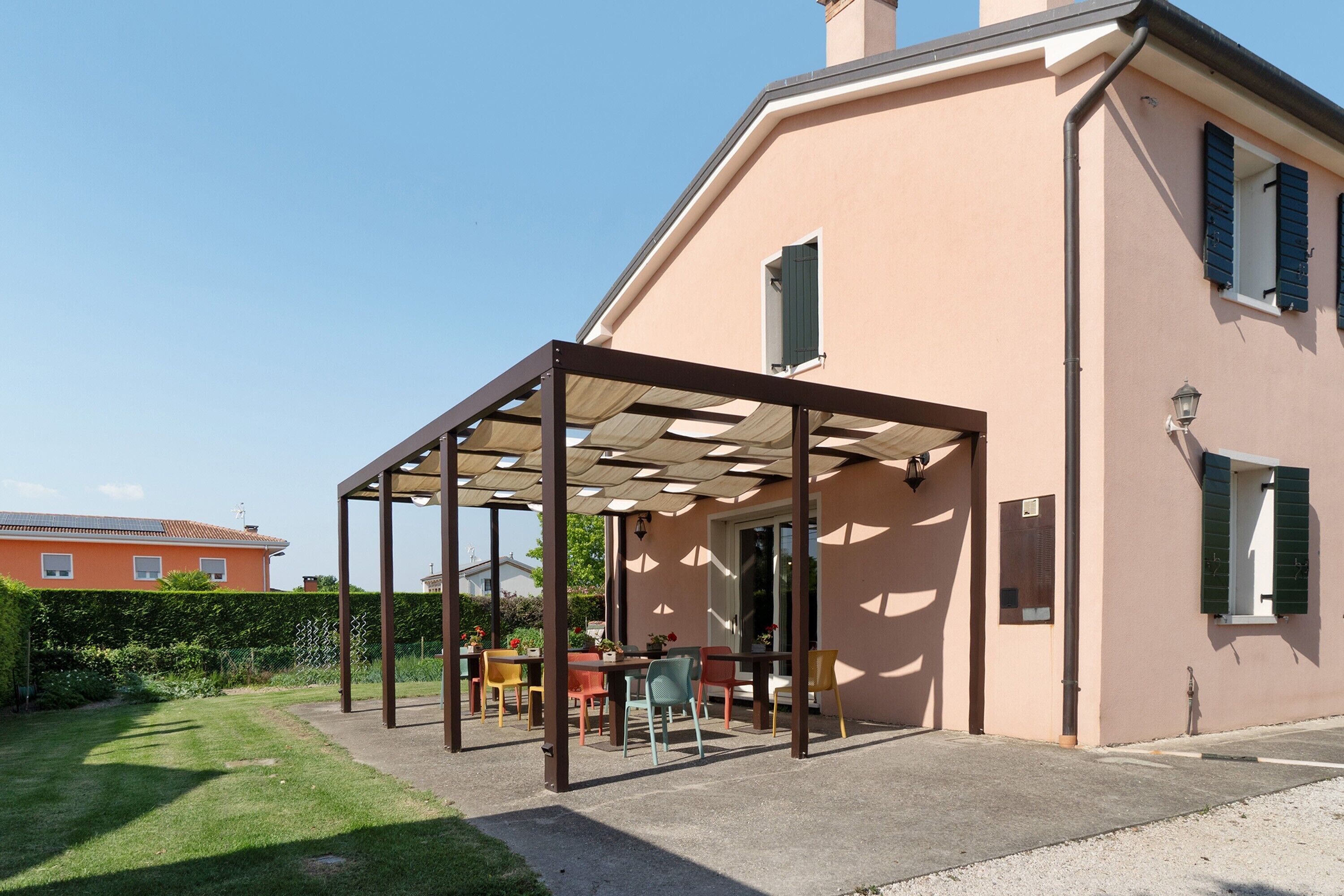 A house with a covered patio, a lawn, and a neighboring building.