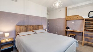 A bedroom with a bed, bedside table, lamp, and a wooden desk with a chair. - Melloni Street Home - Malva Room (Dolo)