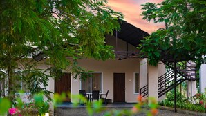 A building with a covered patio, outdoor seating, and a staircase. - Dream Habitat Resort (Bhadravathi)