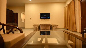 A hotel lobby with a flat-screen TV mounted on the wall, a reception desk, a wooden chair, and a glass railing. - Dream Habitat Resort (Bhadravathi)