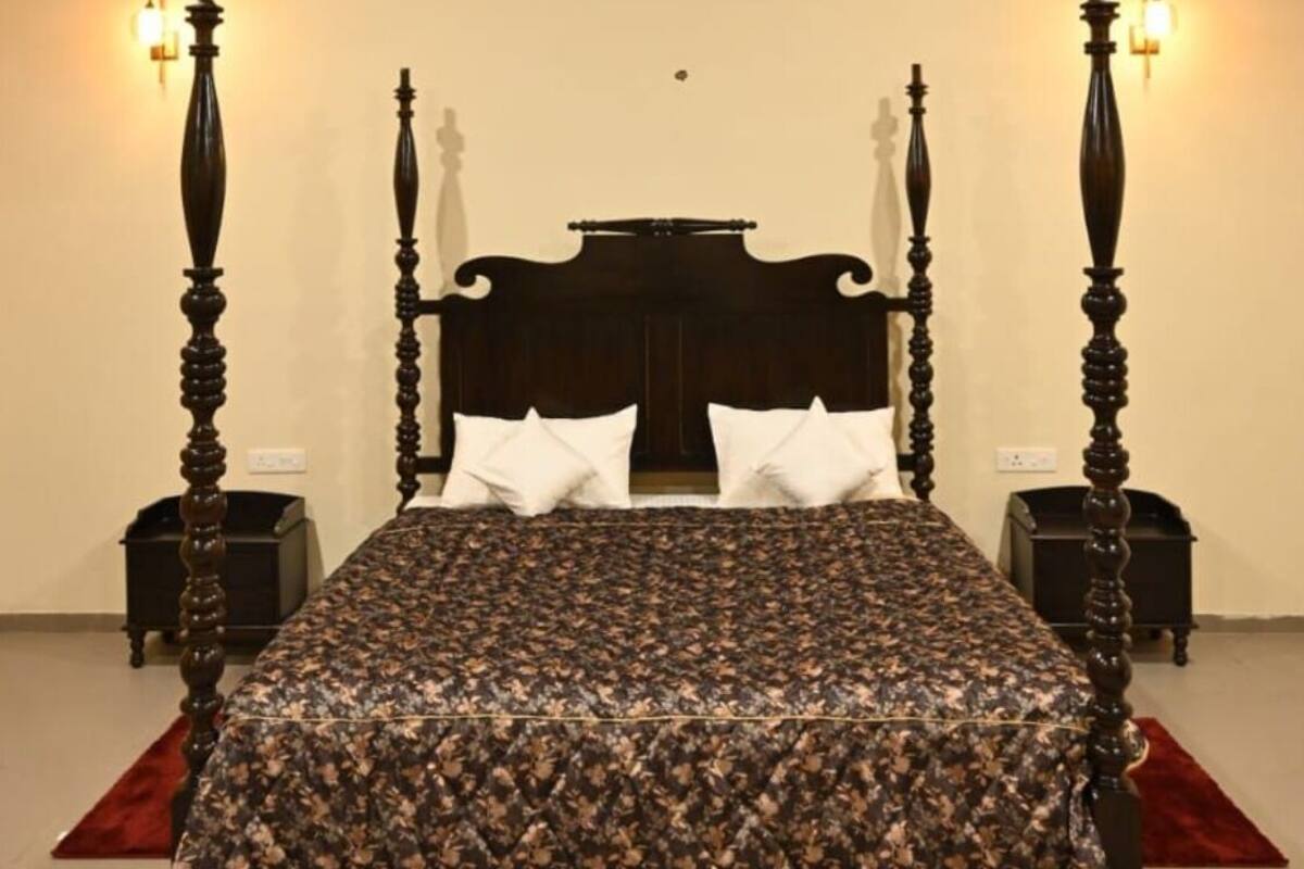 A four-poster bed with a dark wooden headboard, two bedside tables with lamps, and a ceiling fan.