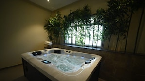 A hot tub in a room with a view of bamboo plants through a window. - Dream Habitat Resort (Bhadravathi)