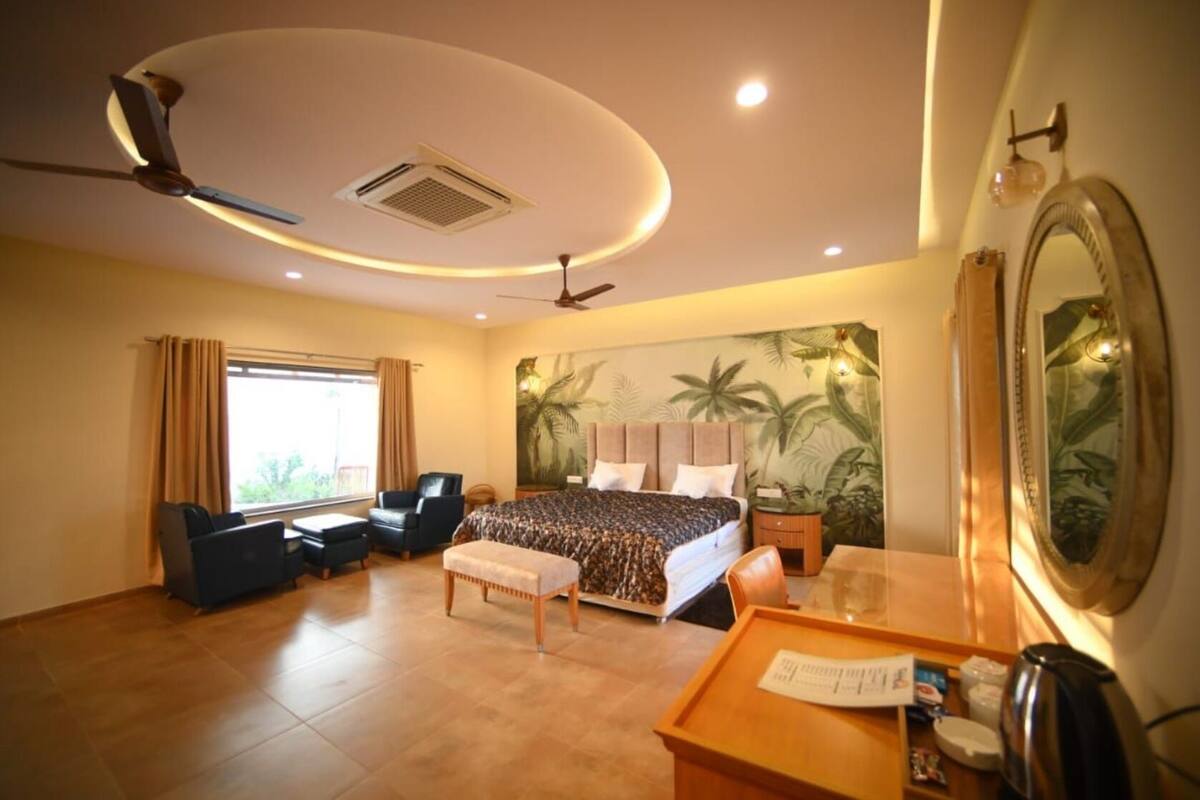 A hotel room with a bed, desk, chair, and a large mirror.