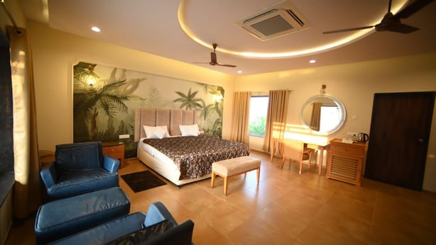 A bedroom with a bed, a desk, a chair, a round mirror, and a ceiling fan. - Dream Habitat Resort (Bhadravathi)