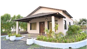 A single-story house with a tiled roof, a front porch, and a garden with various plants. - Dream Habitat Resort (Bhadravathi)
