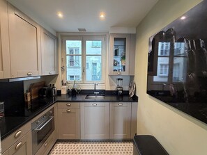 Eine moderne Küche mit schwarzem Arbeitsplatz, Edelstahlgeräten und einem Fenster mit Blick auf die Stadt.