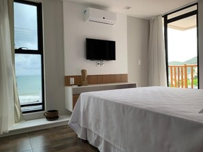 A hotel room with a bed, a TV mounted on the wall, a window with a view, and an air conditioning unit. - Swell Praia Hotel (Natal)
